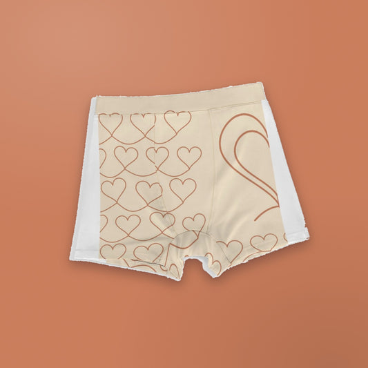 Better Half men's boxer briefs laid flat on a terracotta background: cream fabric with terracotta line-drawn hearts and one half of a large heart outline, white side panels