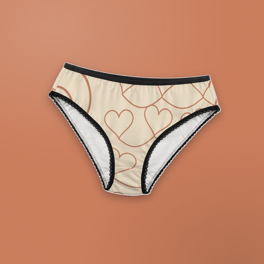Other Half women's lace briefs laid flat on a terracotta background: cream fabric with terracotta line-drawn hearts and the other half of a large heart outline, black lace trim